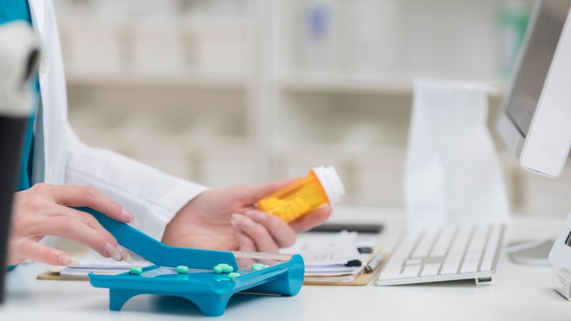 Pharmacist preparing medication for a customised blister pack