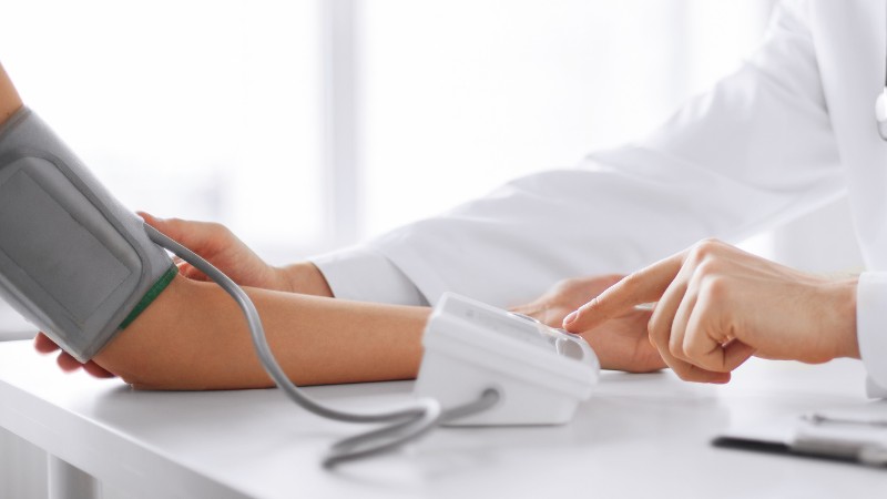 Pharmacist measuring blood pressure providing consultation to a patient during a blood pressure screening appointment.